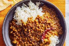 a bowl filled with beans and rice next to tortilla chips on a table