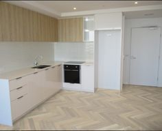 an empty kitchen with white cabinets and wood flooring on the walls is seen in this image