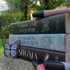 four books stacked on top of each other in front of a tree and grass area