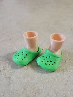 pair of green shoes with holes on them sitting on the floor next to a cup