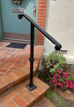 a metal hand rail on the steps leading up to a front door with pink flowers