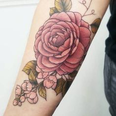 a woman's arm with a pink rose tattoo on the left side of her arm