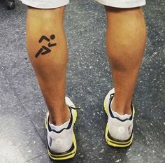 the legs and ankles of a person with tattoos on their feet, standing in front of an escalator