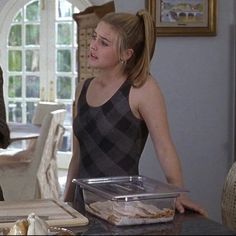 a woman standing in front of a table with food on it and an older man looking at her