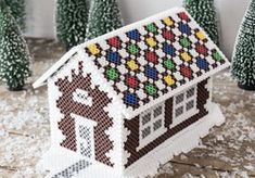 a small house made out of plastic beads with trees in the background and snow on the ground