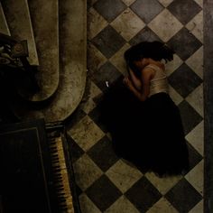 a woman sitting on the floor next to a piano