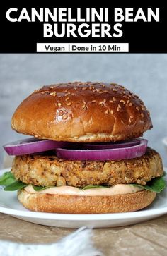 a burger with lettuce, onion and cheese on it sitting on a white plate