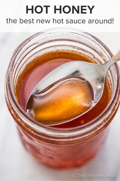 a spoon full of hot honey sitting in a jar with the words hot honey on it