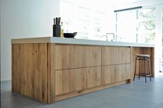 an image of a kitchen with wooden cabinets and stools on the counter top in front of a window