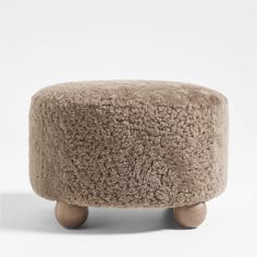 the foot stool is made out of sheepskin and has wooden legs, which are attached to