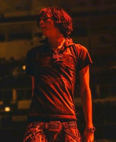 a young man standing on top of a stage with his hands in his pockets and looking off to the side