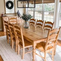 a dining room table and chairs in front of a large window with wreath on it