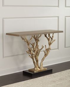 a table with some branches on it in front of a white wall and carpeted floor