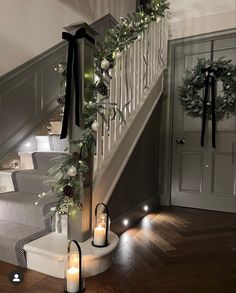 candles are lit on the stairs next to christmas wreaths and garlanded garlandes