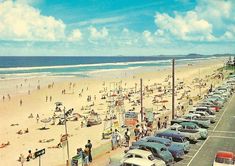 many cars are parked on the beach and people are in the water at this time