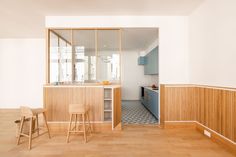 an empty kitchen and dining room with wood flooring, white walls and wooden stools