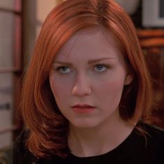 a woman with red hair is looking at the camera