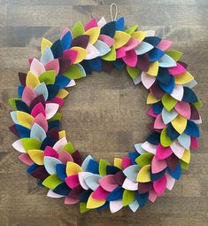 a colorful wreath made out of felt sitting on top of a wooden floor