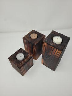 three wooden candle holders sitting on top of a white table