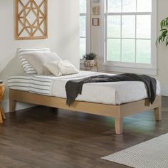 a bed sitting on top of a wooden floor next to a window