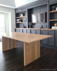 a large wooden table sitting in the middle of a room with built - in bookshelves