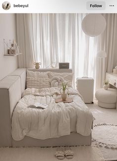 a white couch sitting in front of a window next to a table with a potted plant on it