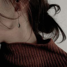 a close up of a person wearing a sweater and earring on their left side