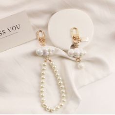 a pair of earrings with pearls hanging from it's earring hooks on top of a white cloth