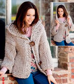 a woman wearing a sweater and jacket with buttons on the front, sitting against a brick wall