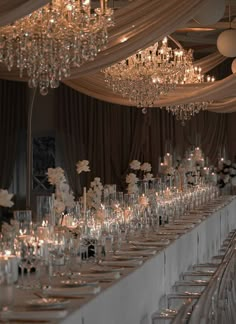 a long table covered in lots of candles and vases with flowers on them is set up for a formal function