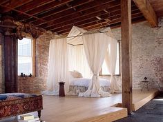 a bedroom with four poster bed and white drapes