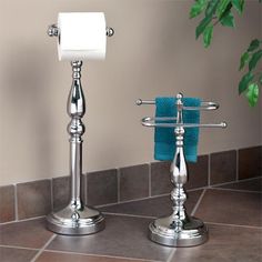 two silver candlesticks with towels on them and a potted plant in the background