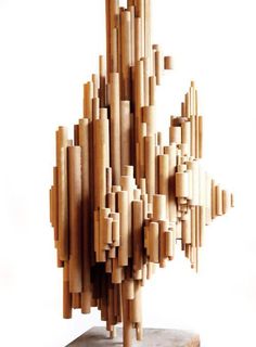 a sculpture made out of wooden sticks on top of a block of wood with white background