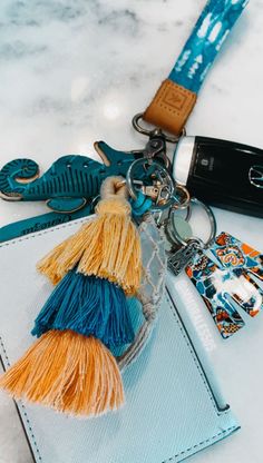 a keychain that has some tassels attached to it and is sitting on top of a card holder