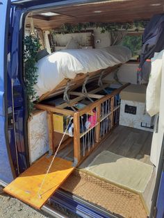 a blue van with bunk beds in it's back door and stairs leading up to the bed