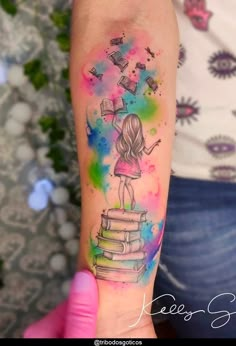 a person with a tattoo on their arm holding a stack of books in the air