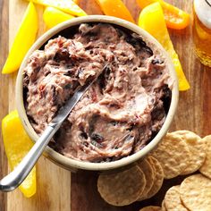 a bowl filled with fruit dip surrounded by crackers and orange peels on a cutting board