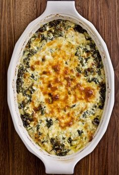 a casserole dish with cheese and spinach in it on a wooden table