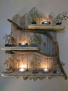 three wooden shelves with lit candles on them in the shape of trees and branches, against a white wall