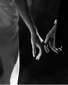 black and white photograph of two people holding each other's hands with their fingers