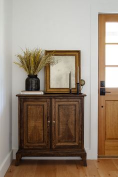 a wooden cabinet with a mirror and vase on top