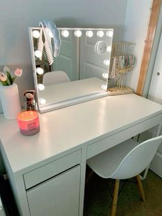 a white desk topped with a vanity mirror and a lit up candle on top of it