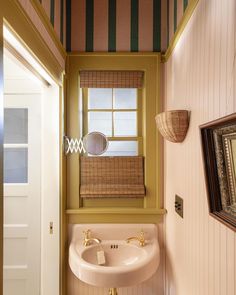 a bathroom sink sitting under a window next to a wall mounted mirror and framed pictures