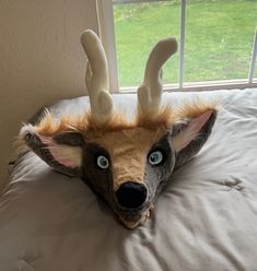 a stuffed deer head laying on top of a bed