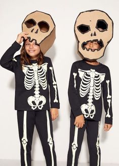 two children wearing skeleton pajamas with their faces in the shape of a human head and torso