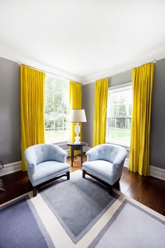 a living room with yellow curtains and two chairs in front of a large window on the far wall