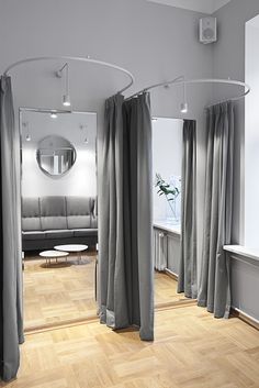 a living room filled with furniture next to a large window covered in grey drapes