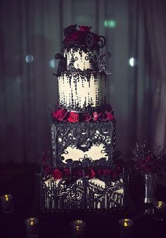 a three tiered wedding cake with red roses on the top and black icing