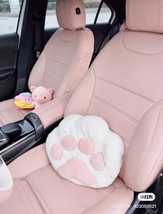 the interior of a car with pink leather seats and stuffed animals on the back seat