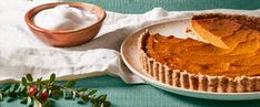 a piece of pie sitting on top of a white plate next to a wooden bowl